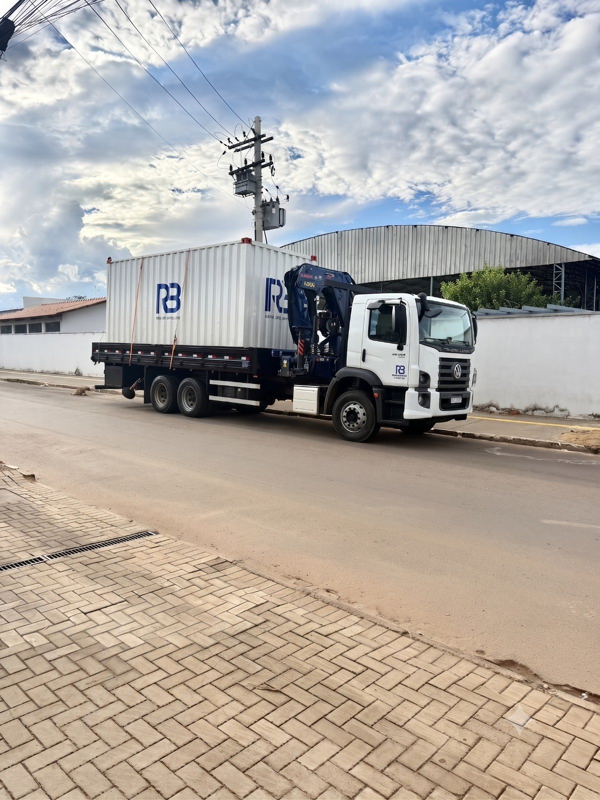 Caminhão munck da RB transportando container e estrutura metálica
